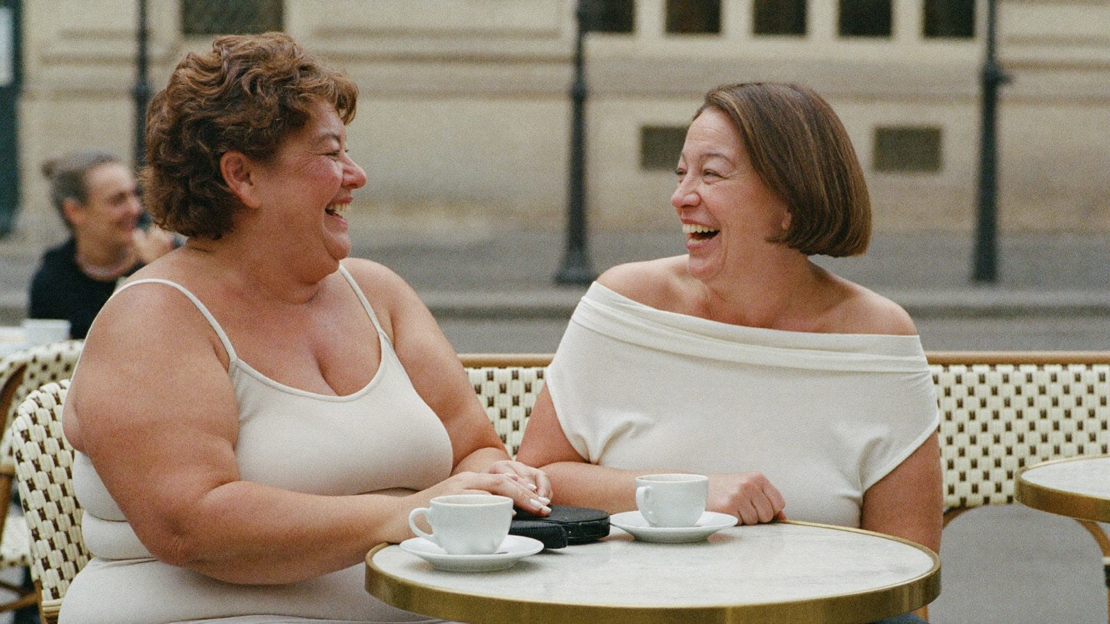 Two women at a Paris cafe in a camisole and an off-the-shoulder top